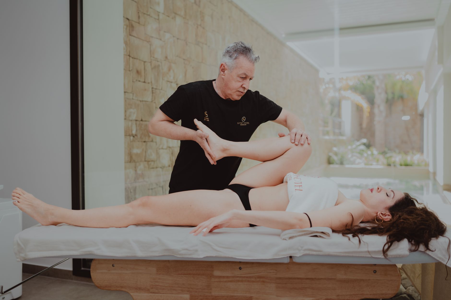 Kỹ thuật viên hỗ trợ người bệnh vận động chân trên bàn trị liệu